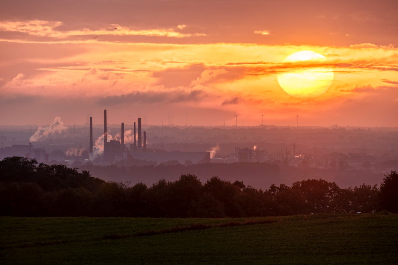 Services A stunning sunset over an industrial landscape with smoke rising from factory chimneys.