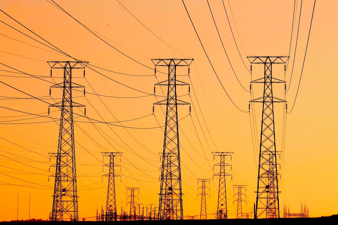 Services Silhouetted power lines against a vibrant orange sunset, symbolizing energy and infrastructure.